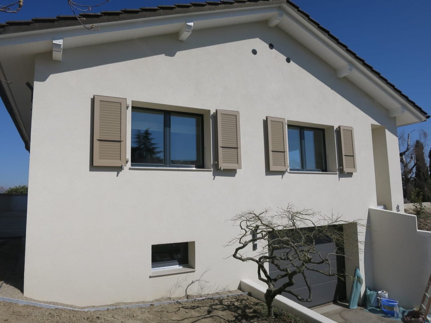 Maison suisse rénovée avec sa façade blanche et de nouvelles fenêtres
